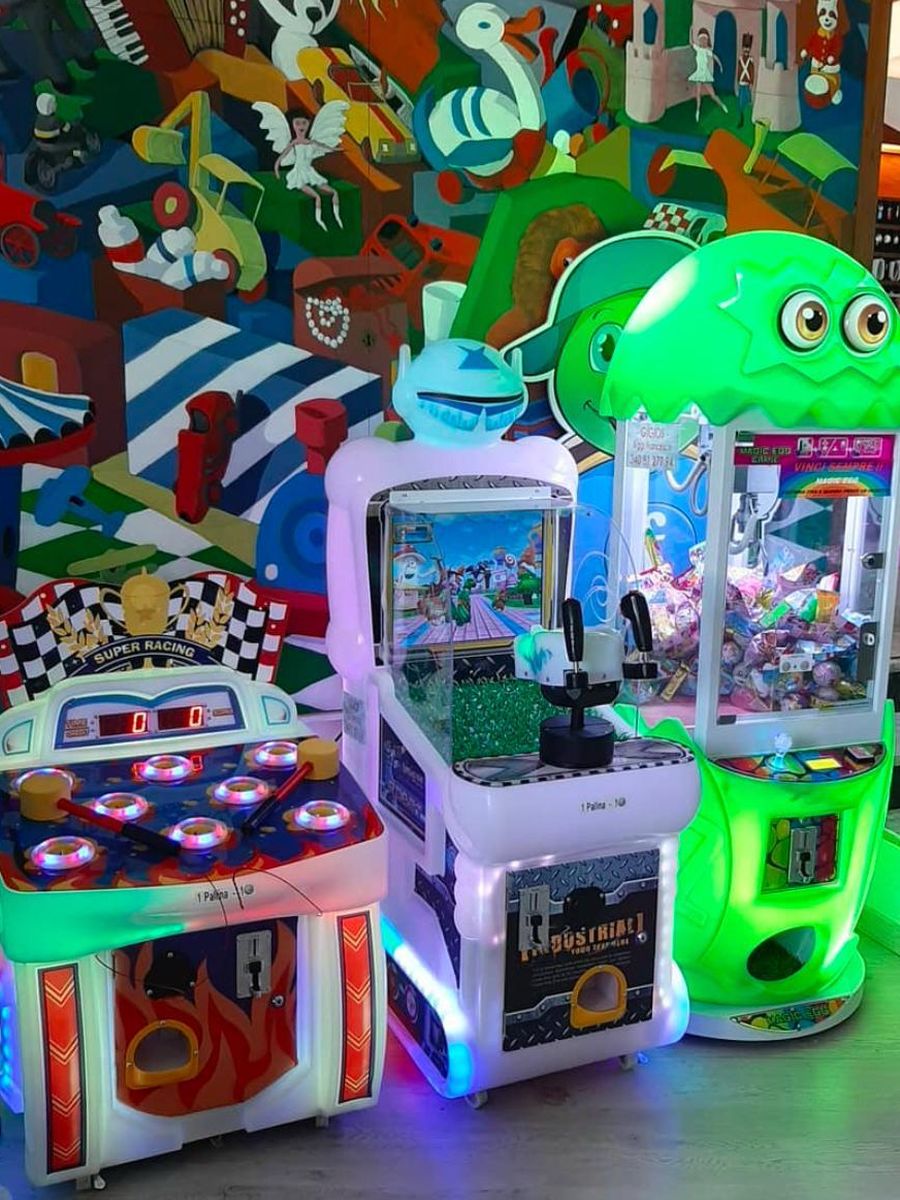 Tre giochi Gigios davanti a una parete con murales: gru acchiappa-premi verde, gioco con la cloche e gioco del martello